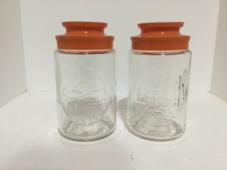 Two Vintage Anchor Hocking Glass Tang Jars Cabin And Church With Orange Lids