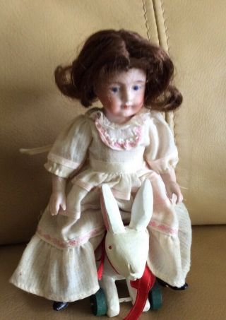 Antique All Bisque Doll Sitting On A Rabbit