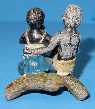 old lead figure of a black boy comforting a girl sitting on a log 2