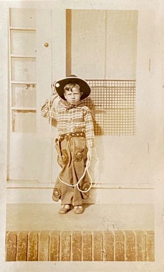 Snapshot little boy in cowboy suit & hat standing on porch 2