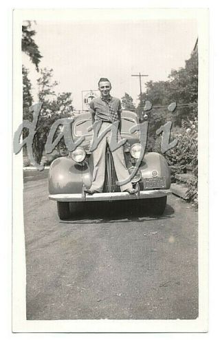 Young Man Standing On The Front Bumper Of An Antique Car 1937 Photo