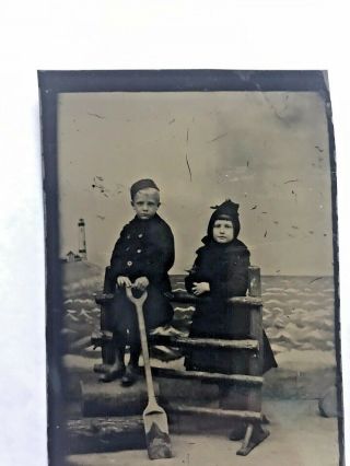 Tintype Of Two Children Holding A Wooden Shovel And Light Scene In Background