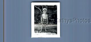 Found B&w Polaroid C,  7926 Boy In Swimsuit And Hat Standing By Plants