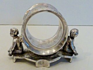 Silver Plated Napkin Ring W/ A Cherub Seated On Either Side Of Japanesque Ring