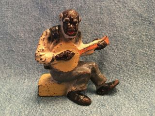 Cast Iron Figurine Of Black Man Seated And Playing Banjo